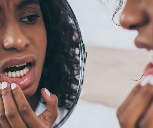 Woman checking her gum line in mirror looking for decay